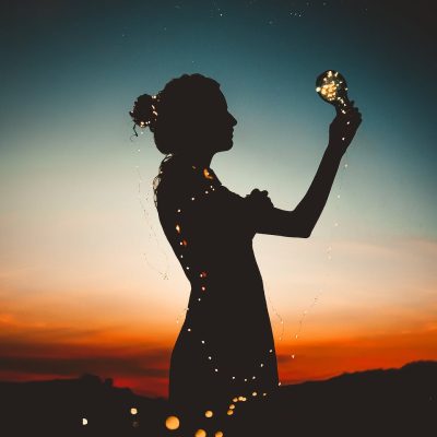 woman holding lit up light string silhouette photography