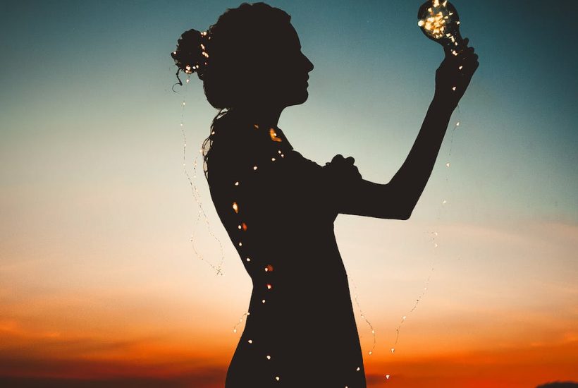 woman holding lit up light string silhouette photography
